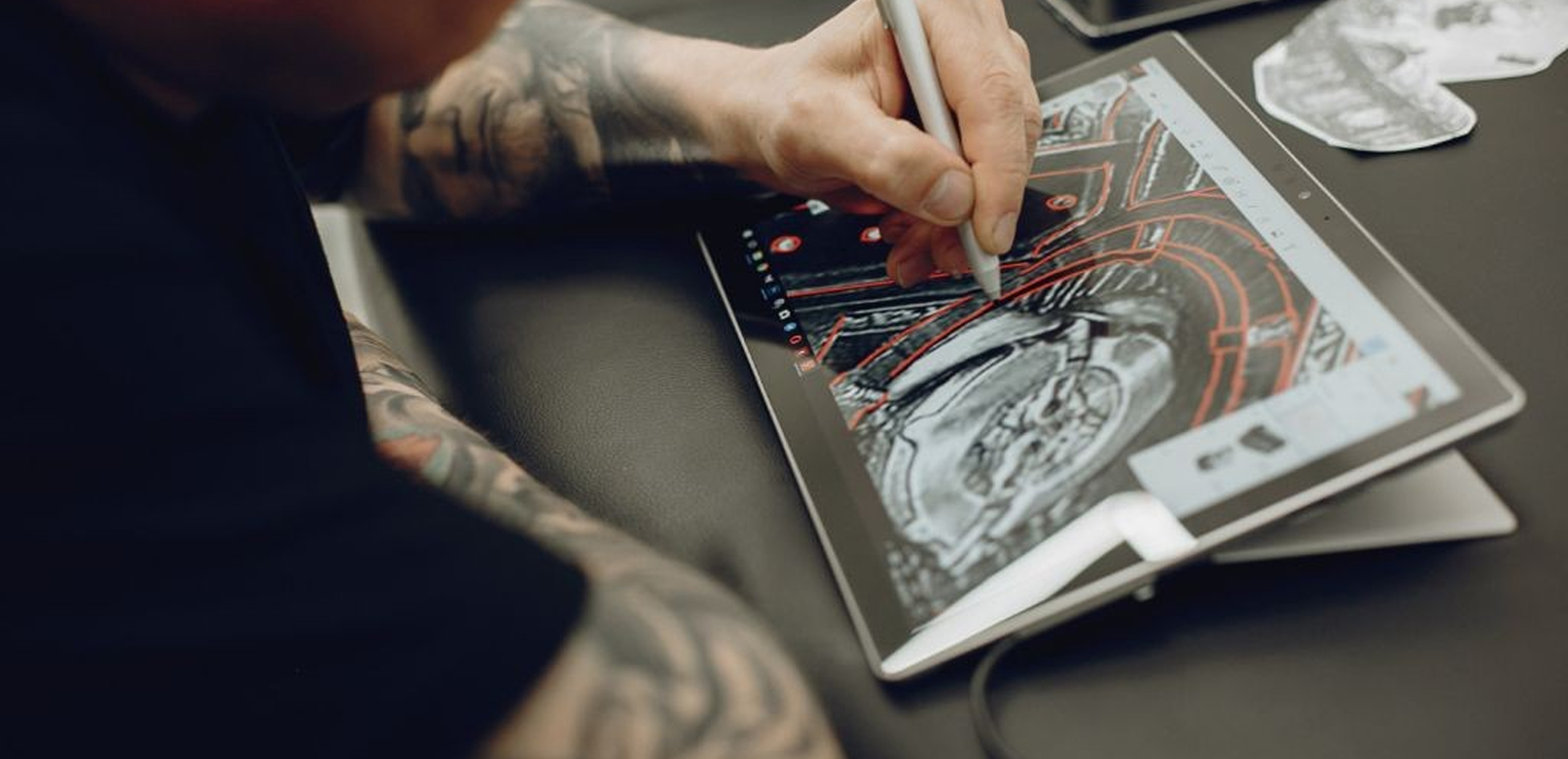 Man with tattoos drawing on notepad